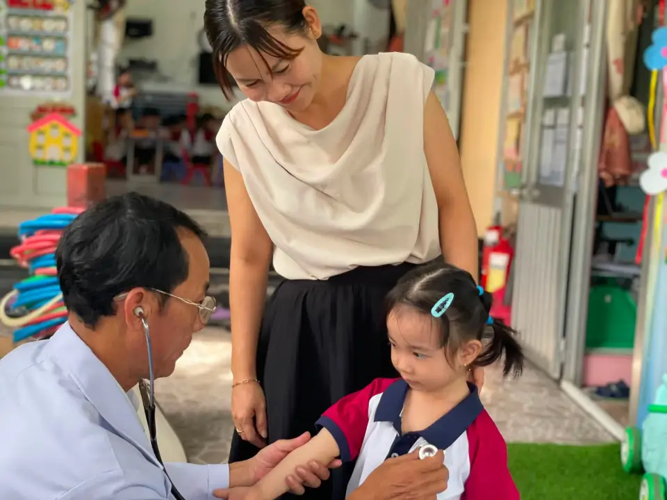 Cô giáo đồng hành cùng bé trong buổi khám sức khỏe