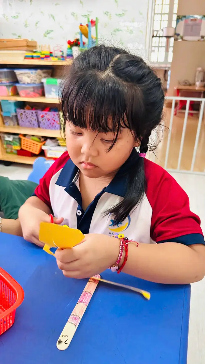 Bé lớp Voi Hồng tập cắt giấy màu để làm cánh chuồn chuồn