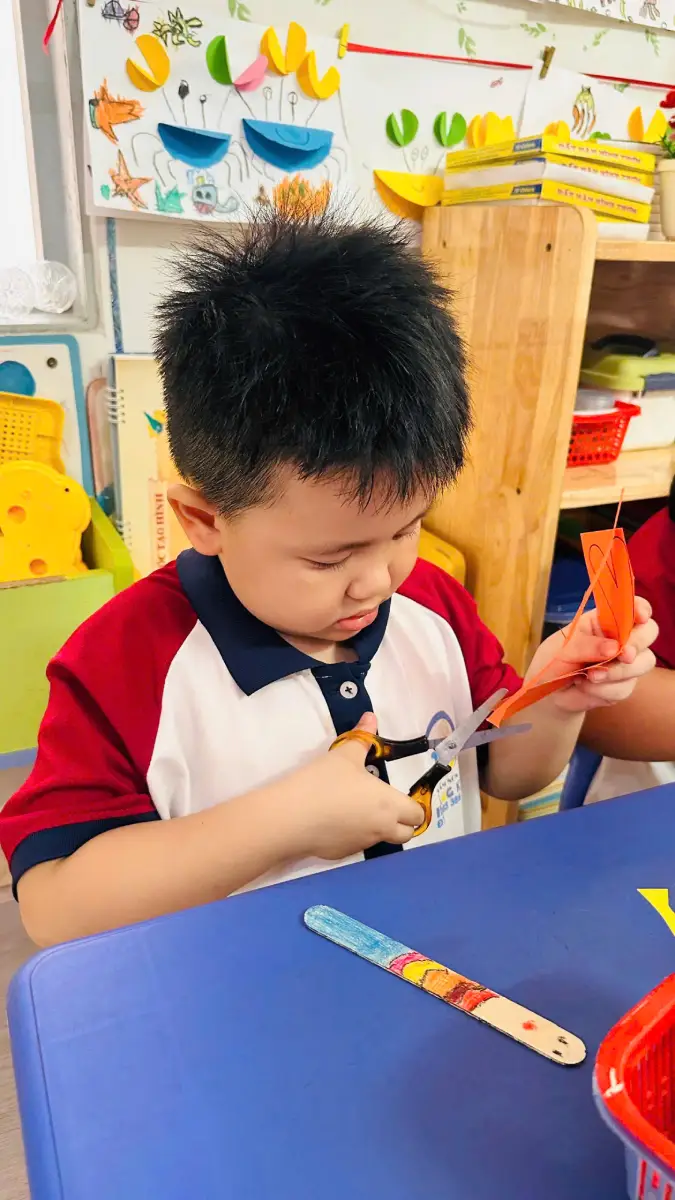Bé tập trung sử dụng kéo trong hoạt động tạo hình