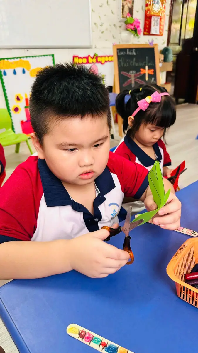 Bé chăm chú hoàn thiện sản phẩm tạo hình từ giấy màu