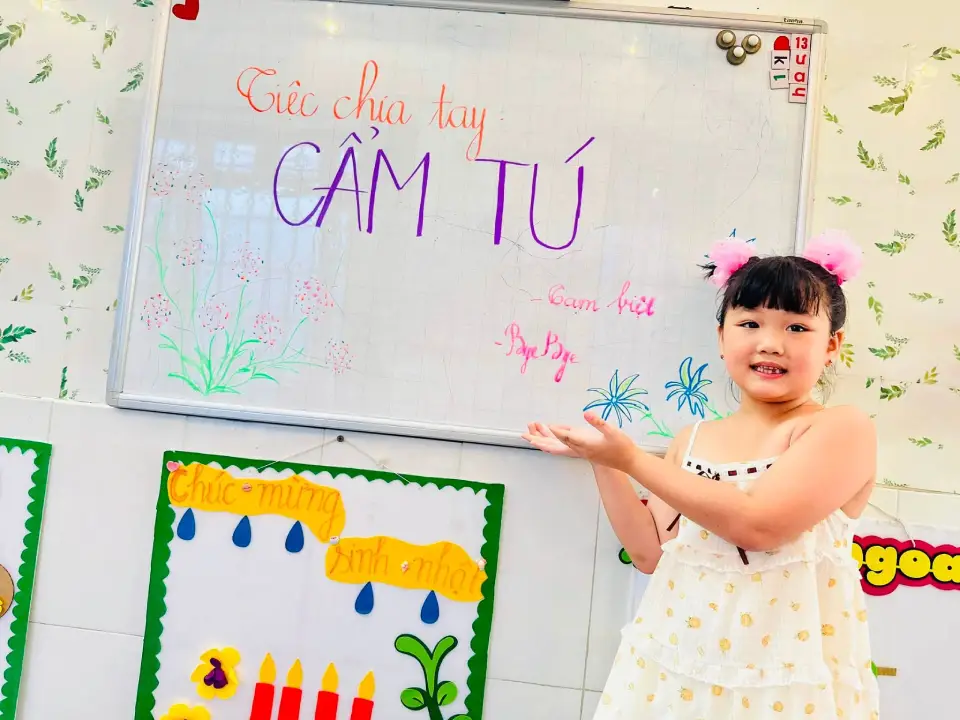 Bé Cẩm Tú bên bàn tiệc chia tay tại trường